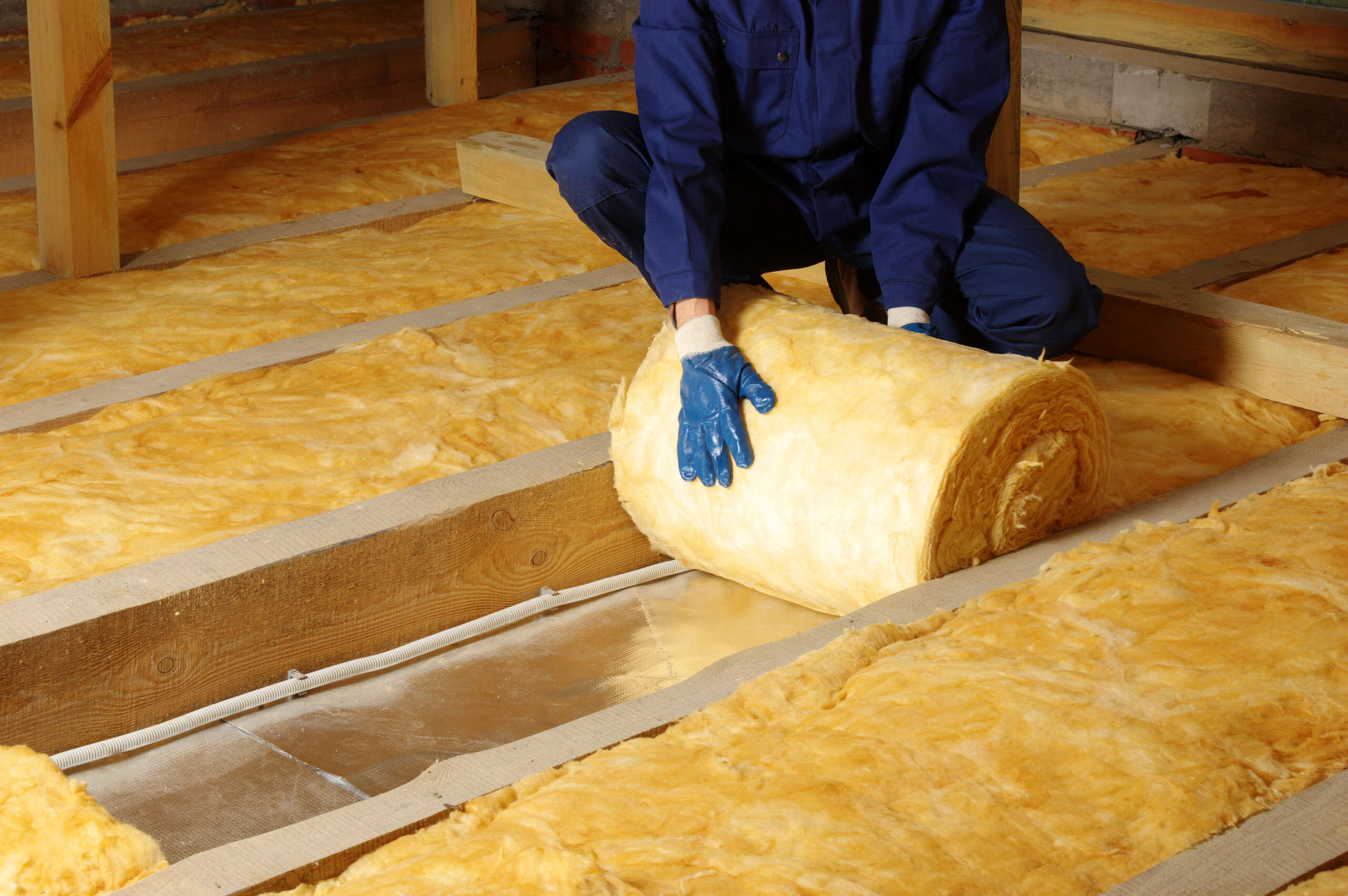 worker fitting acoustic floor insulation